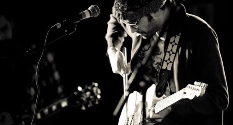 A photo of folk singer-songwriter J. Schnitt playing the guitar. Photo courtesy of J. Schnitt.